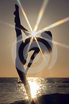 woman practicing stretching at sunset. seaside background, silhouette