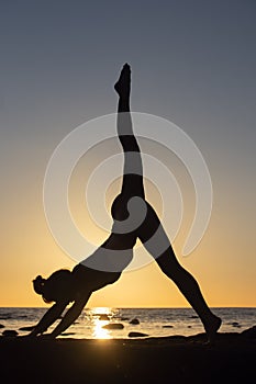 woman practicing stretching at sunset. seaside background, silhouette