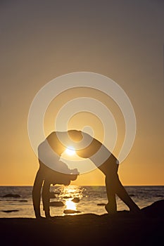 woman practicing stretching at sunset. seaside background, silhouette