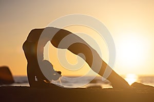 woman practicing stretching at sunset. seaside background, silhouette