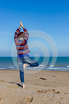 Woman practicing yoga on the beach