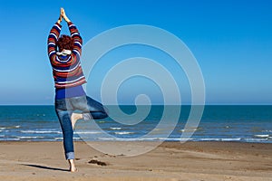 Woman practicing yoga on the beach