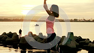 Woman practicing yoga on the beach at sunset