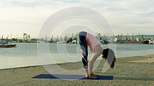 Woman practicing yoga on the beach at sunset
