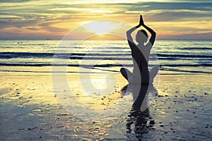 Woman practicing yoga on the beach at sunset in Thailand. Lotus.