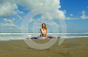 Young happy and attractive girl doing flexibility exercise with legs split  on sand in wellness harmony health care and fitness