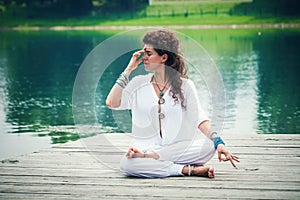 Woman practicing yoga breathing technique by the lake