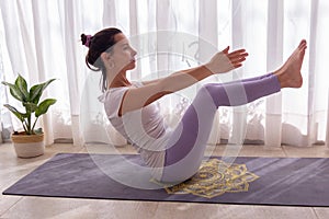 Woman practicing yoga in a bright room on a mandala yoga mat