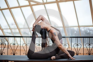 Woman practicing yoga concept, doing Eka Pada Rajakapotasana exercise, One Legged King Pigeon pose, working out wearing black spor