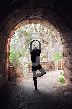 Woman practicing yoga in a dark tunnel