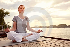 Woman practicing yoga on dock by river
