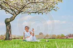 Woman is practicing yoga, doing Ardha Matsyendrasana pose near blossom tree