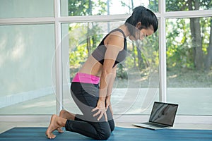 Woman practicing yoga, doing upward abdominal lock exercise, uddiyana Bandha pose,  working out, wearing sportswear, watching