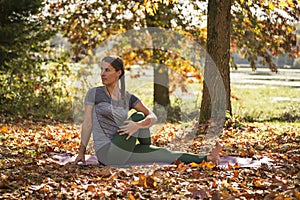 Woman practicing yoga among fall leaves and autumnal colours