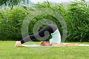 Woman practicing Yoga Halasana Plow pose photo