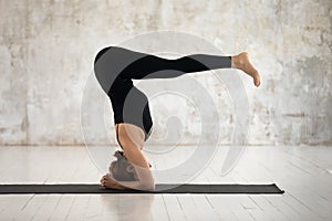 Woman practicing yoga, headstand, variation of salamba sirsasana exercise