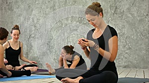 Woman practicing yoga at health club. Young girls talking and relaxing after fitness, Yoga instructor texting on the