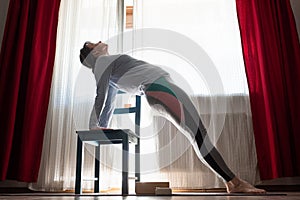 Woman practicing yoga indoors at home doing Upward Plank Pose