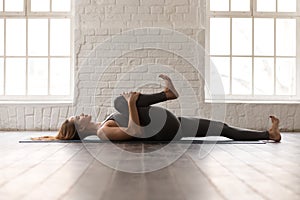 Woman practicing yoga, lying in Knees to Chest pose, Apanasana photo