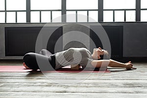 Woman practicing yoga in Reclined Butterfly exercise, supta baddha konasana