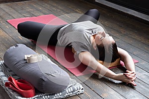 Woman practicing yoga in Reclined Butterfly exercise, supta baddha konasana photo