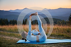 Woman practicing yoga outdoors in the mountains in a serene, natural setting.