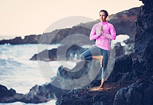 Woman practicing yoga outside seashore