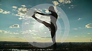 Woman practicing yoga in the park at sunset