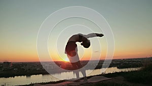 Woman practicing yoga in the park at sunset