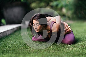 Woman practicing yoga performing yoga-asanas outdoors.