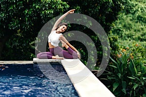 Woman practicing yoga performing yoga-asanas outdoors.