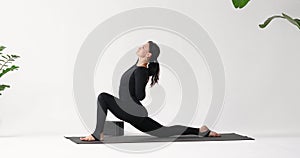 A woman practicing yoga performs longitudinal lunge anjaneyasana and ardha hanumanasana with gomukhasana