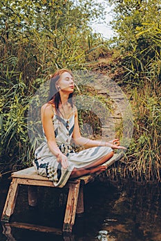 Woman practicing yoga on pier by river.