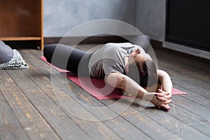 Woman practicing yoga in Reclined Butterfly exercise, supta baddha konasana