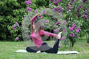 Woman practicing yoga on rug near bushes of photo