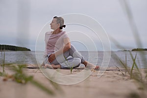 Woman practicing yoga at the sandy beach.
