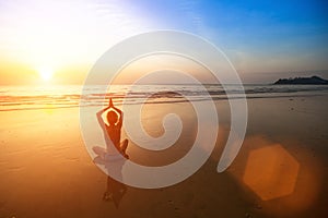 Woman practicing yoga on sea beach during wonderful sunset.