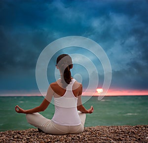 Woman Practicing Yoga by the Sea at Sunset