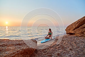 Woman practicing yoga on seashore. Meditation on beach at sunset. Relax in nature. Contemplation and meditation idea