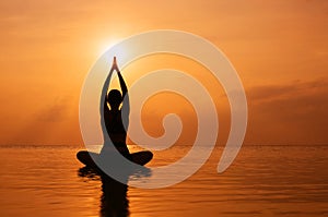 Woman practicing yoga, silhouette on the beach at sunset