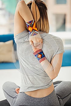 Woman practicing yoga, sitting in Cow Face exercise, Gomukasana pose, indoor interior background