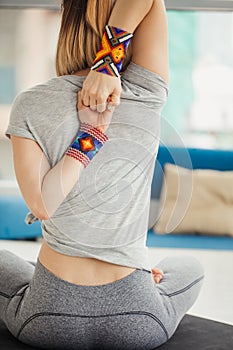 Woman practicing yoga, sitting in Cow Face exercise, Gomukasana pose, indoor interior background