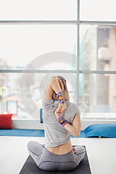 Woman practicing yoga, sitting in Cow Face exercise, Gomukasana pose, indoor interior background