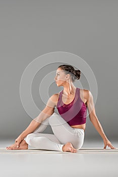 woman practicing yoga, sitting in Half lord of the fishes exercise, Ardha