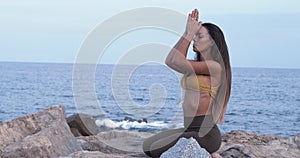 Woman practicing yoga on some rocks with the sea on the horizon.Mindfulness, Meditation