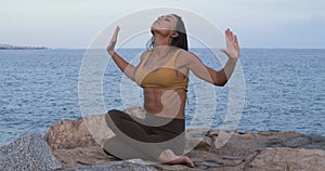 Woman practicing yoga on some rocks with the sea on the horizon.Mindfulness, Meditation