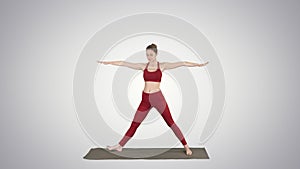 Woman practicing yoga, standing in Extended Side Angle exercise, Utthita parsvakonasana pose on gradient background.