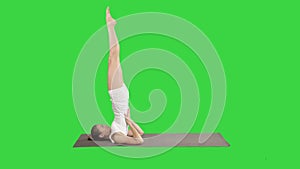 Woman practicing yoga, standing in salamba sarvangasana exercise, supported Shoulder stand pose on a Green Screen