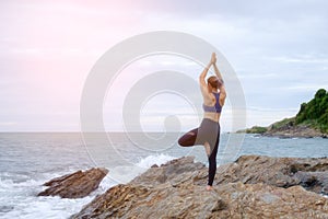 The woman practicing yoga sunset on the beach.