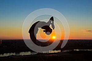 Woman practicing yoga at sunset - drop back, wheel pose